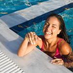 Woman in a pink swimsuit smiling by a pool