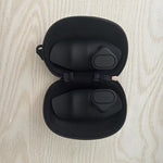 Black earbud case with earbuds inside on a light wood surface