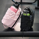 Pink and black water bottle holders with water bottles on a dark surface