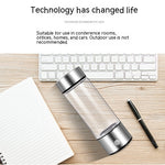 Clear water bottle with silver base on a desk with keyboard and notebook