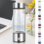 Clear water bottle with silver top on a desk next to a laptop and flowers
