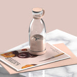 Glass bottle with a metallic cap on a magazine with a pink background