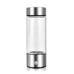 Clear glass bottle with silver lid and base on a white background
